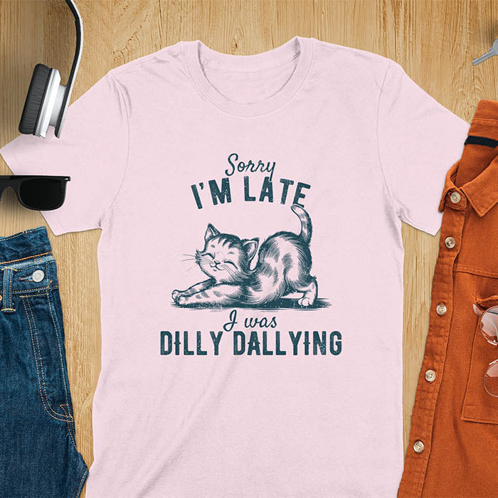 A t-shirt with a kitten stretching its back. Text: Sorry I'M LATE above and I was DILLY DALLYING below. This cat lover shirt features cat cuteness gift and kawaiiness cuteness. A sarcastic meme shirt about dilly dally, a funny genz meme with funny animals. This kawaii kitten design has vintage aesthetics, a snarky humorous tee, an animal person gift or mom gift hers. A cat mom t shirt alternative.