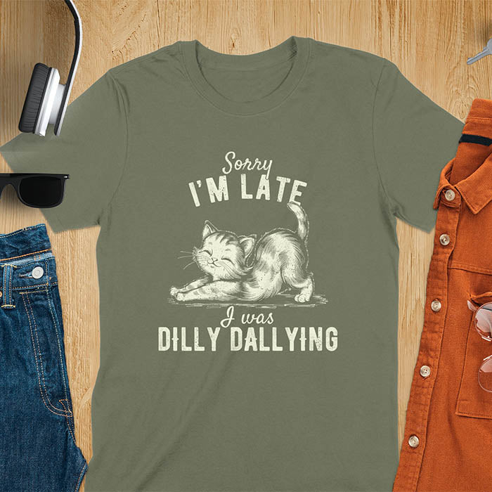A t-shirt with a kitten stretching its back. Text: Sorry I'M LATE above and I was DILLY DALLYING below. This cat lover shirt features cat cuteness gift and kawaiiness cuteness. A sarcastic meme shirt about dilly dally, a funny genz meme with funny animals. This kawaii kitten design has vintage aesthetics, a snarky humorous tee, an animal person gift or mom gift hers. A cat mom t shirt alternative.