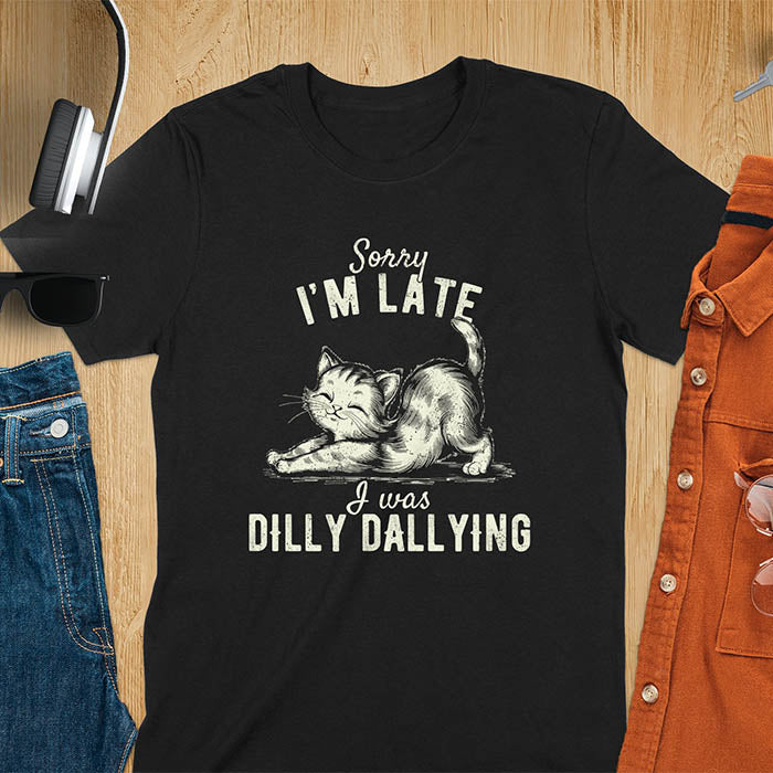A t-shirt with a kitten stretching its back. Text: Sorry I'M LATE above and I was DILLY DALLYING below. This cat lover shirt features cat cuteness gift and kawaiiness cuteness. A sarcastic meme shirt about dilly dally, a funny genz meme with funny animals. This kawaii kitten design has vintage aesthetics, a snarky humorous tee, an animal person gift or mom gift hers. A cat mom t shirt alternative.
