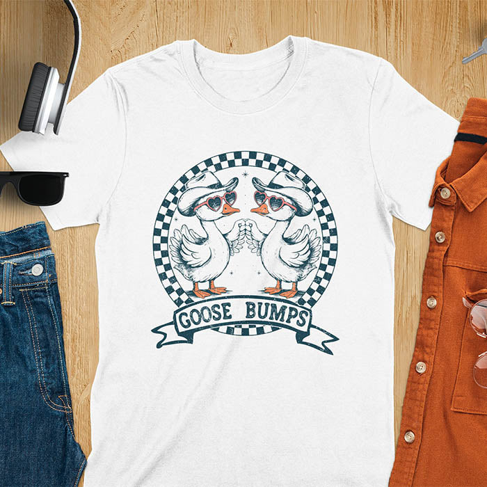 A t-shirt with two geese in cowboy hats and heart sunglasses, within a checkered circle, touching wings. Banner reads "GOOSE BUMPS". This Retro Goose Bump Shirt is a sarcastic goose, silly goose crewneck, Funny Sarcastic Silly Meme Tee. An unhinged tee, weirdcore meme, Snarky Sassy Saying Tee-shirt. A Hilarious Tshirt Gift, gift for goose lover, cowboy cowgirl gift, animal person, gift mom hers, cute animal clothe. Features kawaiiness cuteness.