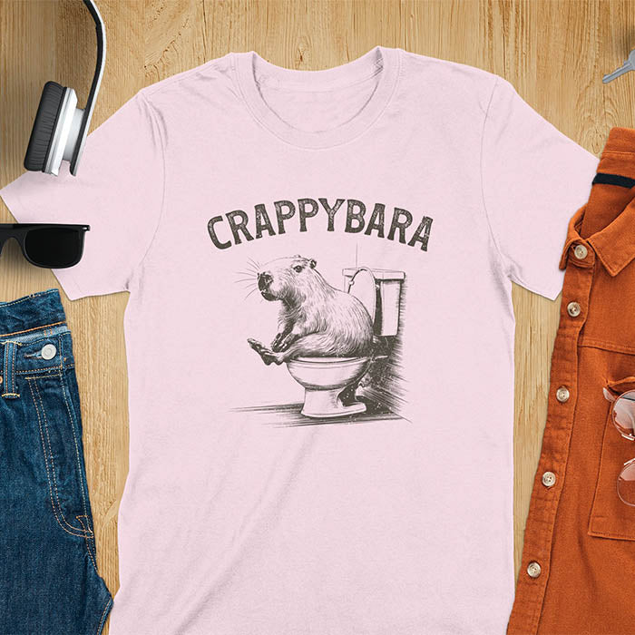 A t-shirt with a capybara on a toilet. Text: "CRAPPYBARA". This Crappybara Tshirt is an inappropriate shirt, offensive shirt & Toilet Humor Gag Gift. A Funny Meme Tee-shirt, Trending meme shirt, genz gen z weirdcore t-shirt. Features Kawaiiness Kawaiiful, Capybara cuteness, Weird capybara gift, Funny Vintage Capybara Shirt. For animal person gift, pet lovers tee, Animal Lover T-shirt, gift mom hers. A Y2K tee-shirt, Vintage Silly Party Tees, shirts that go hard.