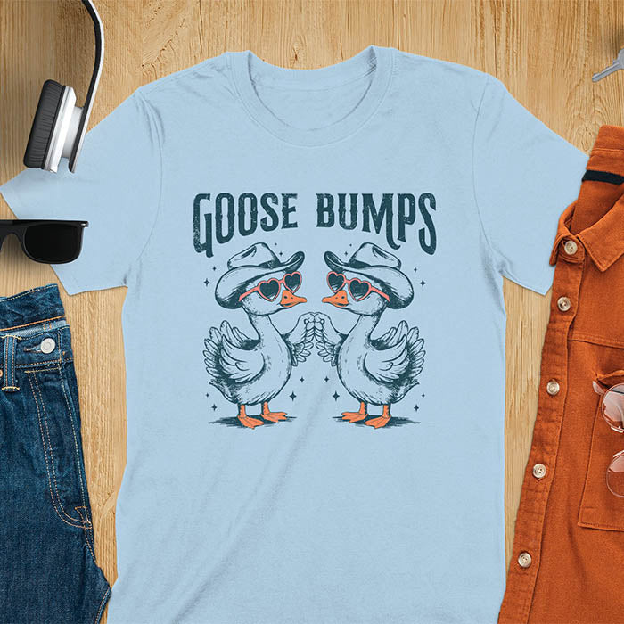 A t-shirt with two geese in cowboy hats and heart sunglasses touching wings. The phrase "GOOSE BUMPS" is positioned above them. This Goose Bumps T-shirt is a silly goose crewneck, funny goose shirt, Retro Vintage Humorous Tee Gift. A Western Sarcastic Silly Meme Shirt, Snarky Sassy Saying Tee-shirt, unhinged tee-shirt, funny sarcasm gift, funny outfit. Ideal gift for goose lover, animal person, Animal Lover Tshirt, gift mom hers. Features kawaiiness cuteness, cute animal clothe, cowboy aesthetic.