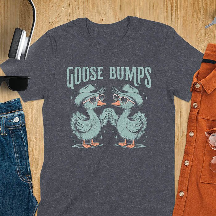 A t-shirt with two geese in cowboy hats and heart sunglasses touching wings. The phrase "GOOSE BUMPS" is positioned above them. This Goose Bumps T-shirt is a silly goose crewneck, funny goose shirt, Retro Vintage Humorous Tee Gift. A Western Sarcastic Silly Meme Shirt, Snarky Sassy Saying Tee-shirt, unhinged tee-shirt, funny sarcasm gift, funny outfit. Ideal gift for goose lover, animal person, Animal Lover Tshirt, gift mom hers. Features kawaiiness cuteness, cute animal clothe, cowboy aesthetic.