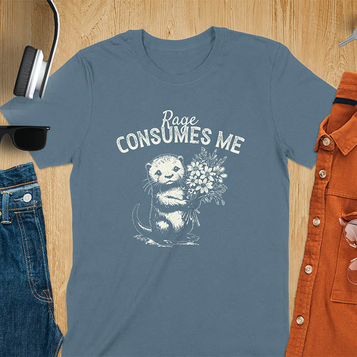 A t-shirt with an otter holding flowers. Text: "Rage CONSUMES ME" above. This dark humor tee features otter cuteness and cuteness kawaii, a mental health meme. A genz meme gift and weird funny t shirt, a funny gag gift or animal lover gag. One of those shirts that go hard, an unhinged tshirt. A mom gift hers or animal person gift with a retro graphic tee style.