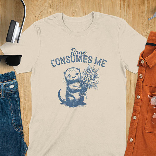 A t-shirt with an otter holding flowers. Text: "Rage CONSUMES ME" above. This dark humor tee features otter cuteness and cuteness kawaii, a mental health meme. A genz meme gift and weird funny t shirt, a funny gag gift or animal lover gag. One of those shirts that go hard, an unhinged tshirt. A mom gift hers or animal person gift with a retro graphic tee style.