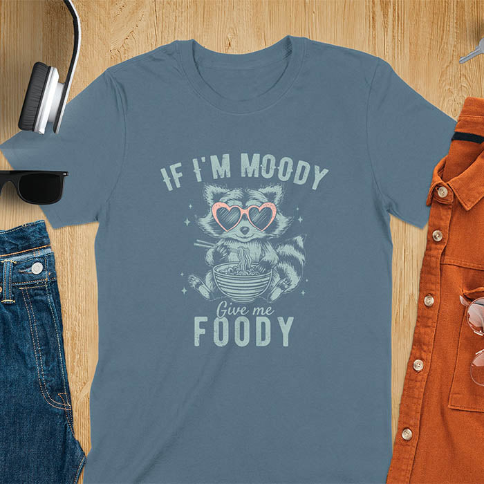 A t-shirt: raccoon in heart sunglasses with noodles. Text: "IF I'M MOODY Give me FOODY". A Funny Raccoon T-shirt, funny trash panda, Vintage Trash Panda Tee. Sarcastic Saying Tee-shirt, snarky humorous, trending funny shirt, meme t shirt, Gag Gift. Features kawaiiness cuteness. Great gift for animal person, Animal Lover Tshirt, mom. Retro aesthetic tee.