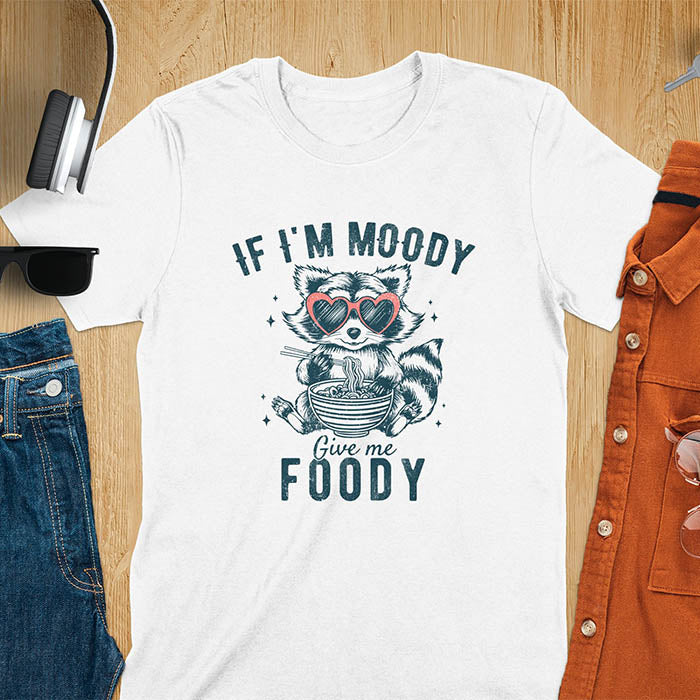 A t-shirt: raccoon in heart sunglasses with noodles. Text: "IF I'M MOODY Give me FOODY". A Funny Raccoon T-shirt, funny trash panda, Vintage Trash Panda Tee. Sarcastic Saying Tee-shirt, snarky humorous, trending funny shirt, meme t shirt, Gag Gift. Features kawaiiness cuteness. Great gift for animal person, Animal Lover Tshirt, mom. Retro aesthetic tee.