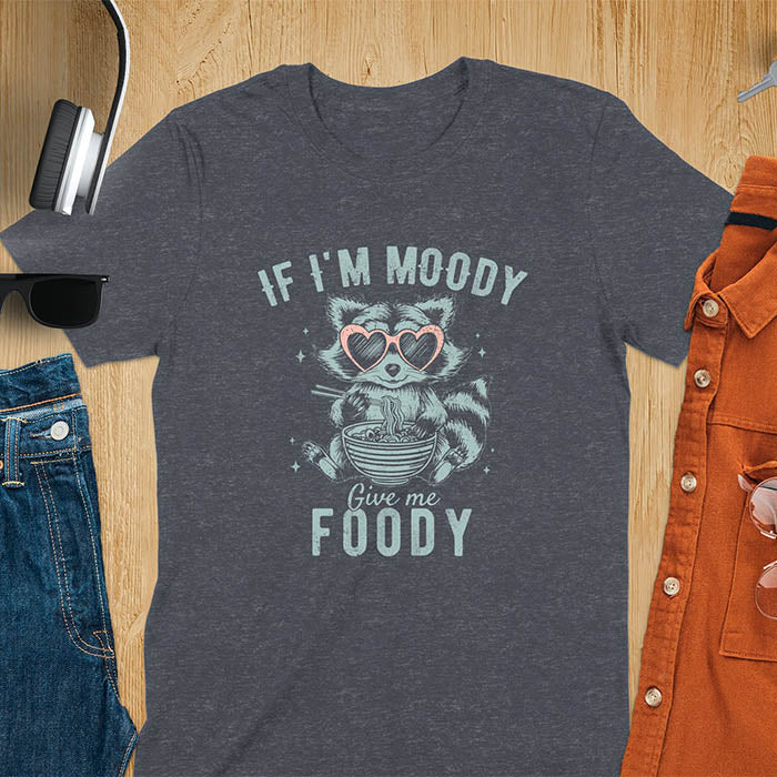 A t-shirt: raccoon in heart sunglasses with noodles. Text: "IF I'M MOODY Give me FOODY". A Funny Raccoon T-shirt, funny trash panda, Vintage Trash Panda Tee. Sarcastic Saying Tee-shirt, snarky humorous, trending funny shirt, meme t shirt, Gag Gift. Features kawaiiness cuteness. Great gift for animal person, Animal Lover Tshirt, mom. Retro aesthetic tee.