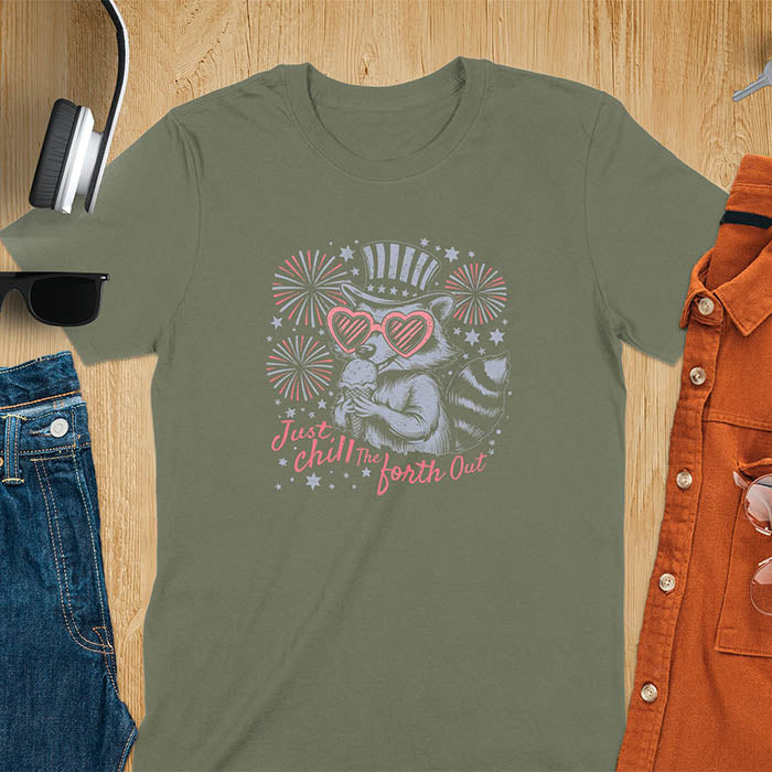 A t-shirt with a raccoon in a patriotic top hat & heart sunglasses, holding an ice cream cone. Fireworks burst around it. Text: "JUST CHILL THE FOURTH OUT". This raccoon cuteness tee is a funny 4th of July fourth of july shirt for chill the 4th out. A fireworks shirt, patriotic merica tee & freedom t shirt for independence day. Has vintage aesthetics, a funny patriot animal person gift or mom gift among 4th of july shirts.