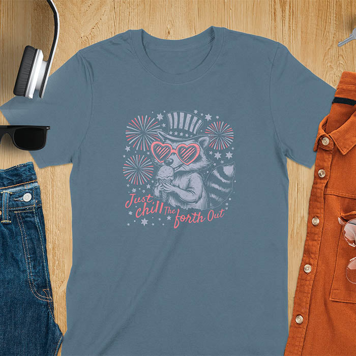 A t-shirt with a raccoon in a patriotic top hat & heart sunglasses, holding an ice cream cone. Fireworks burst around it. Text: "JUST CHILL THE FOURTH OUT". This raccoon cuteness tee is a funny 4th of July fourth of july shirt for chill the 4th out. A fireworks shirt, patriotic merica tee & freedom t shirt for independence day. Has vintage aesthetics, a funny patriot animal person gift or mom gift among 4th of july shirts.