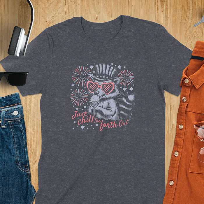 A t-shirt with a raccoon in a patriotic top hat & heart sunglasses, holding an ice cream cone. Fireworks burst around it. Text: "JUST CHILL THE FOURTH OUT". This raccoon cuteness tee is a funny 4th of July fourth of july shirt for chill the 4th out. A fireworks shirt, patriotic merica tee & freedom t shirt for independence day. Has vintage aesthetics, a funny patriot animal person gift or mom gift among 4th of july shirts.