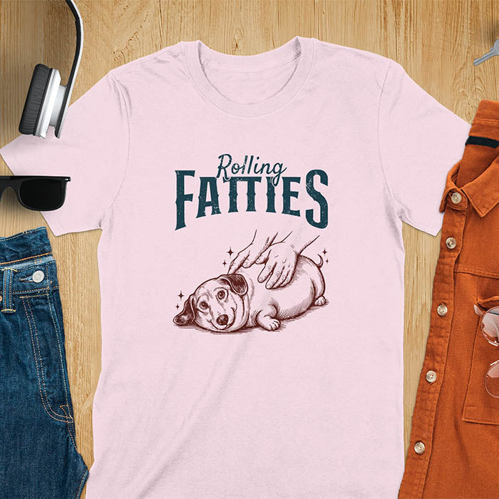 A t-shirt with a retro dog graphic of a dachshund (a doxie or sausage dog pet) lying on its side, happily getting its body rubbed by a pair of human hands. Above the dog, the text reads "Rolling FATTIES". This dog cuteness gift has a vintage aesthetic, perfect for a dog person clothe, dog dad shirt, dachshund mom, or animal person gift. A silly funny shirt for dog pet lovers looking for an animal gag gift or funny memes shirts.