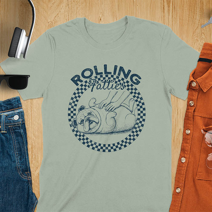 Sage colored unisex t-shirt featuring 'Rolling Fatties' text in blue lettering above a cute chubby bulldog lying on its back within a blue and white checkered circle border