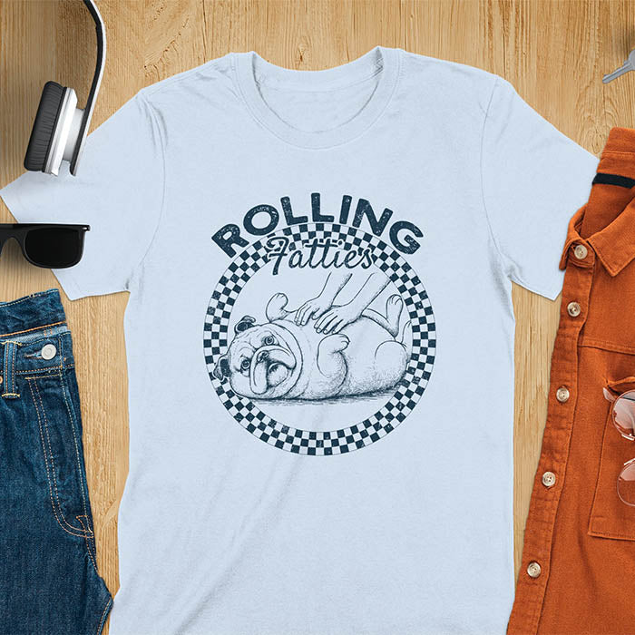 Light blue colored unisex t-shirt featuring 'Rolling Fatties' text in blue lettering above a cute chubby bulldog lying on its back within a blue and white checkered circle border