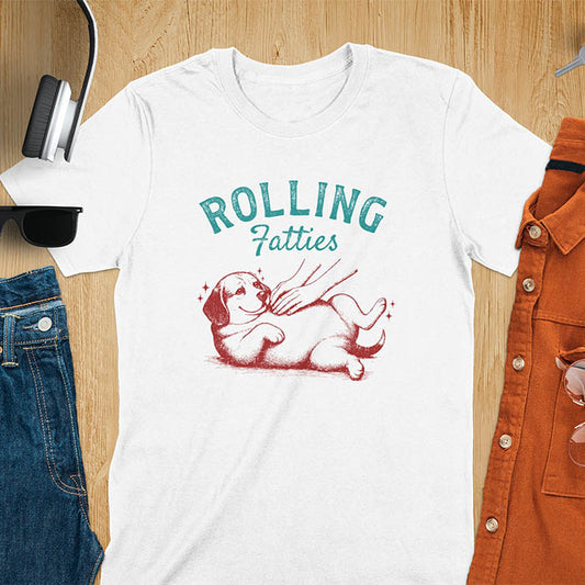 White t-shirt featuring 'Rolling Fatties' text in teal lettering above a chubby beagle dog lying on its back in red/burgundy ink sketch style
