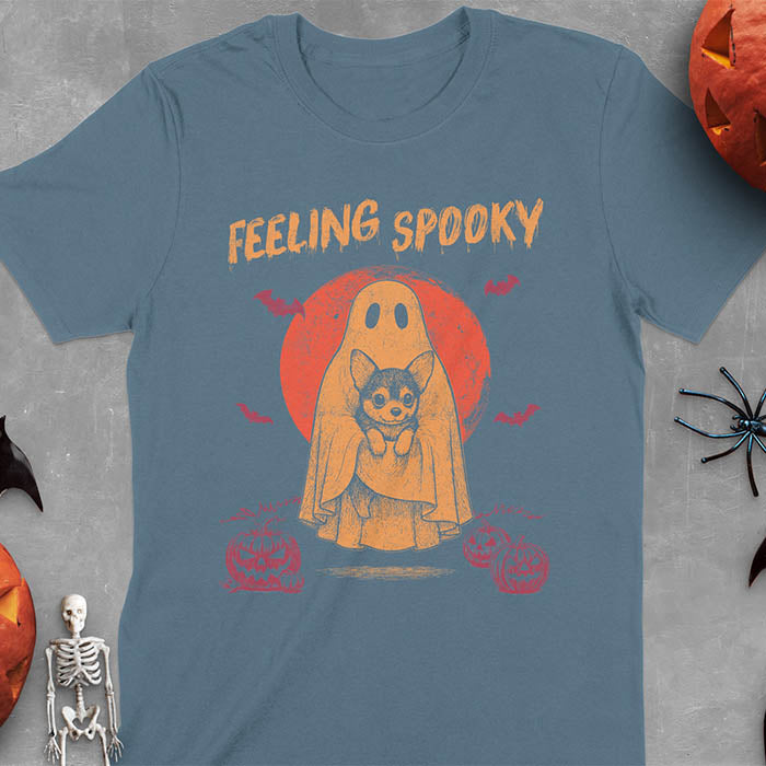 Indigo Blue t-shirt featuring a ghost holding a corgi puppy with 'Feeling Spooky' text above, red moon background with bats and jack-o'-lanterns