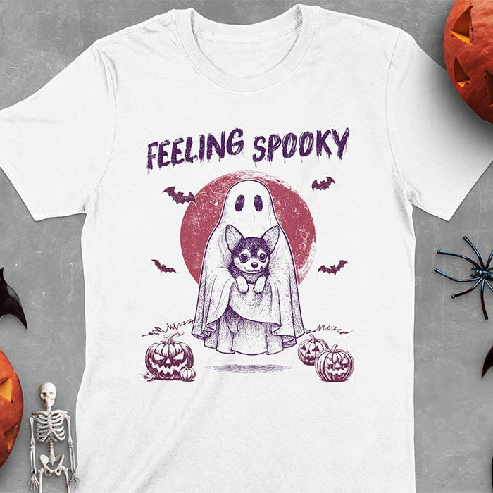White t-shirt featuring a ghost holding a corgi puppy with 'Feeling Spooky' text above, red moon background with bats and jack-o'-lanterns