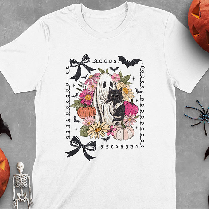 White t-shirt featuring cute ghost holding black cat surrounded by pumpkins, bats, and floral elements in cottagecore coquette style