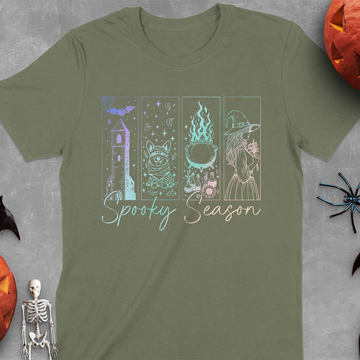 Military Green t-shirt featuring four neon panels with haunted house, mummy corgi, bubbling cauldron, and witch figure, with 'Spooky Season' text below