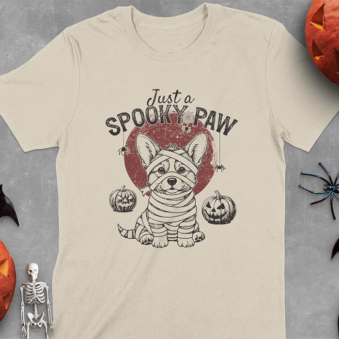 Sand color t-shirt with Halloween mummy corgi featuring "Just a Spooky Paw" text and wrapped corgi graphics