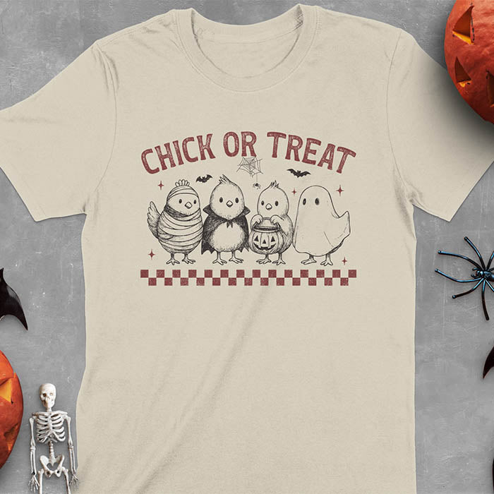 Sand colored t-shirt with Funny Halloween Chick Or Treat text featuring cartoon chickens dressed as spooky characters including ghost, mummy, vampire, and trick-or-treater