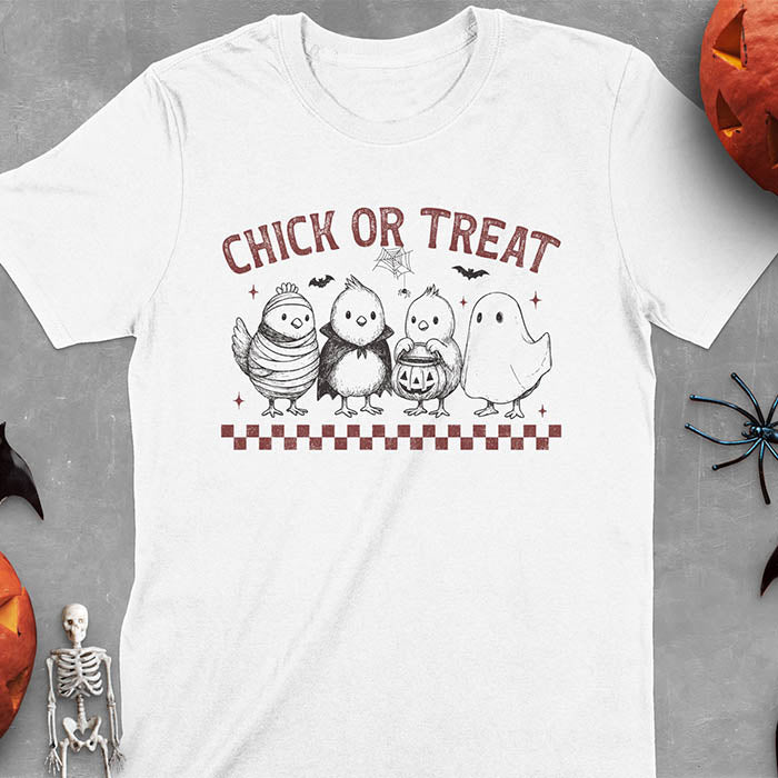 White t-shirt with Funny Halloween Chick Or Treat text featuring cartoon chickens dressed as spooky characters including ghost, mummy, vampire, and trick-or-treater