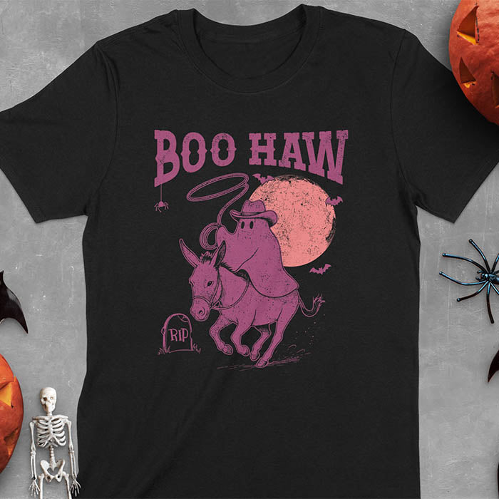 Black t-shirt featuring cowboy ghost riding a donkey with lasso, 'BOO HAW' text above, red moon background with bats and RIP tombstone