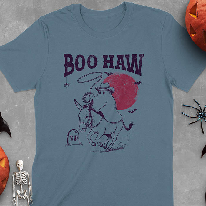 Indigo Blue t-shirt featuring cowboy ghost riding a donkey with lasso, 'BOO HAW' text above, red moon background with bats and RIP tombstone