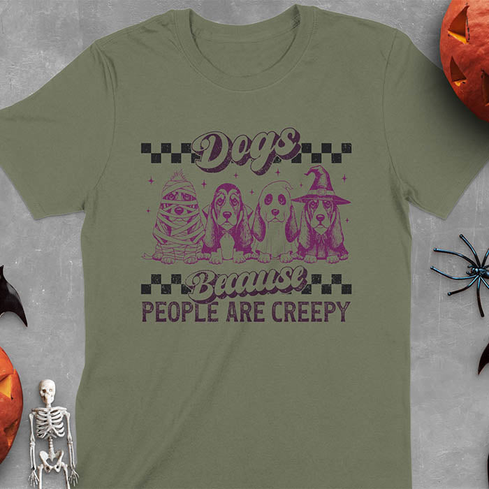 Military Green t-shirt featuring four basset hounds in Halloween costumes - mummy, ghost, witch, and vampire - with 'Dogs Because People Are Creepy' text and checkered borders