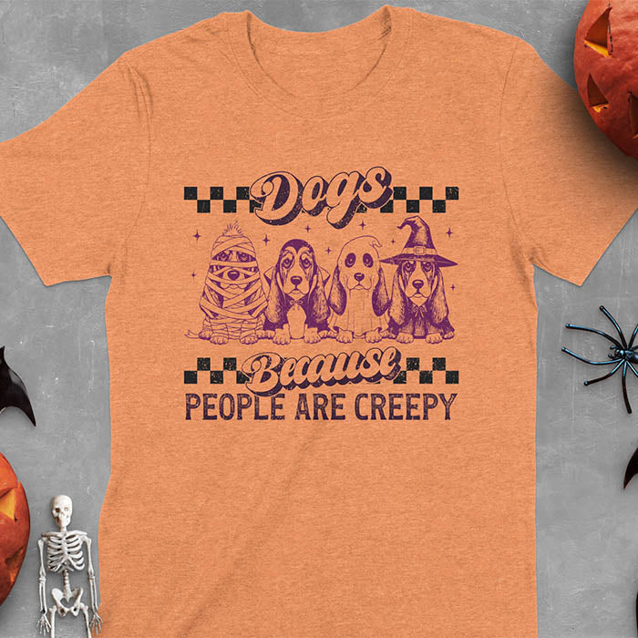 Heather Orange t-shirt featuring four basset hounds in Halloween costumes - mummy, ghost, witch, and vampire - with 'Dogs Because People Are Creepy' text and checkered borders