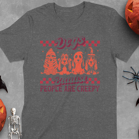 Dark heather t-shirt featuring four basset hounds in Halloween costumes - mummy, ghost, witch, and vampire - with 'Dogs Because People Are Creepy' text and checkered borders