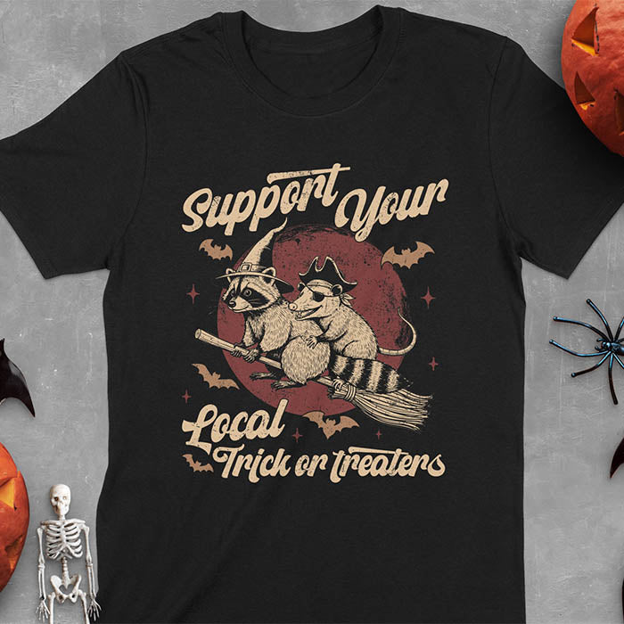 Black t-shirt Halloween witch raccoon design featuring opossum pirate on broom with Support Your Local Trick or Treaters text