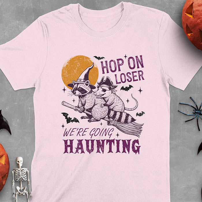 Light pink Halloween witch raccoon and opossum t-shirt with flying broom animal graphics