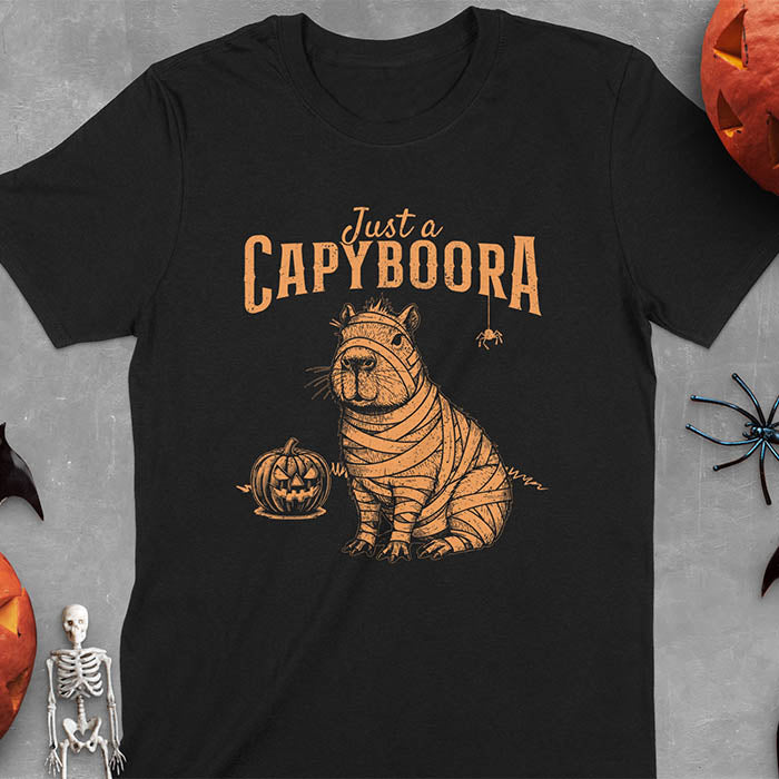 Black t-shirt with a Halloween mummy capyboora t-shirt featuring cute capybara wrapped in white bandages with spooky Halloween design