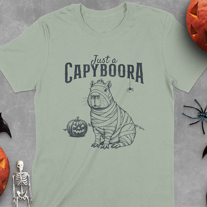 Light green t-shirt with a Halloween mummy capyboora t-shirt featuring cute capybara wrapped in white bandages with spooky Halloween design