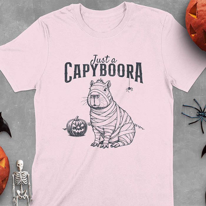 Light Pink t-shirt with a Halloween mummy capyboora t-shirt featuring cute capybara wrapped in white bandages with spooky Halloween design