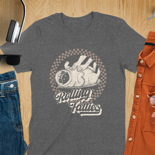 Dark heather t-shirt with 'Rolling Fatties' text and illustration of chubby pug lying on its back inside black and white checkered circle border, with human hands reaching toward pug's belly