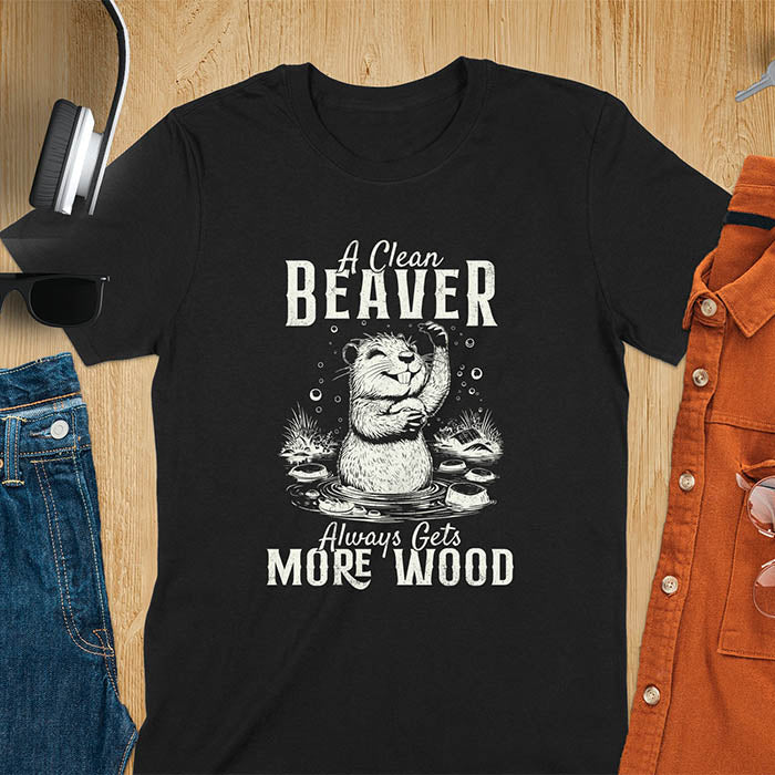 Black t-shirt featuring illustrated beaver bathing in water with text 'A Clean Beaver Always Gets More Wood' - adult humor meme design with cartoon beaver surrounded by water bubbles and tree stumps