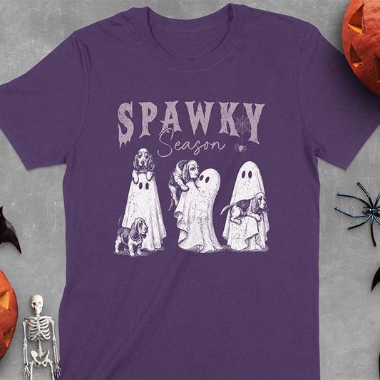 Purple Halloween T-shirt featuring 'SPAWKY Season' text with cute white ghosts carrying Basset Hound puppies, designed in purple ink with playful Halloween theme