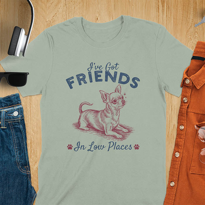 Sage green t-shirt featuring a sitting chihuahua illustration with large ears and paw prints, text reads I've Got Friends In Low Places
