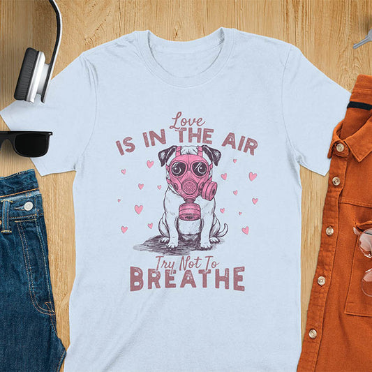 Anti-Valentine's Day pug wearing pink gas mask graphic tee with Love is in the Air Try Not to Breathe text and hearts on light blue shirt