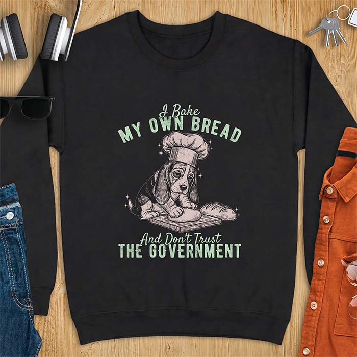 Black sweatshirt with a graphic of a basset hound in a chef's hat kneading dough beside a loaf of bread and the text I Bake My Own Bread And Don't Trust The Government
