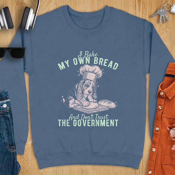 Indigo Blue sweatshirt with a graphic of a basset hound in a chef's hat kneading dough beside a loaf of bread and the text I Bake My Own Bread And Don't Trust The Government