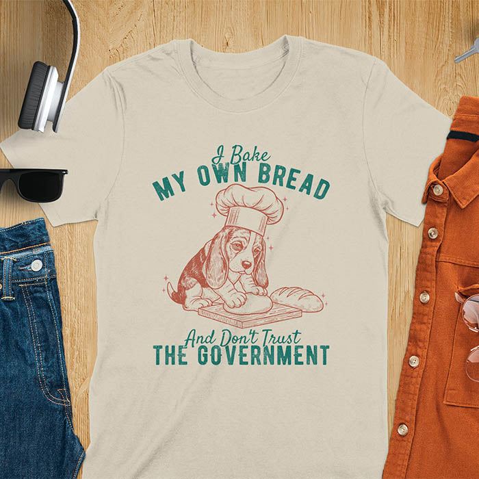 Sand colored Basset Hound chef t-shirt with text 'I Bake MY OWN BREAD And Don't Trust THE GOVERNMENT' featuring basset puppy in chef's hat