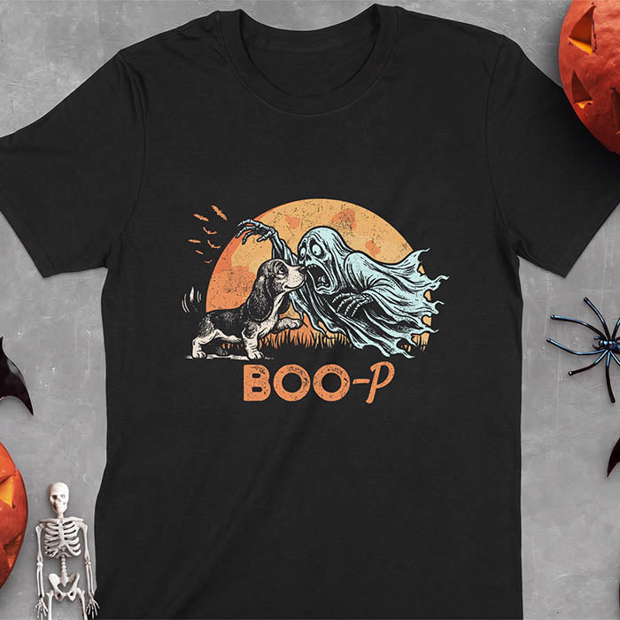 Black t-shirt with a Halloween graphic of a Basset Hound puppy booping a screaming ghost's nose as it reaches out with a skeletal hand with bats flying past a glowing moon and the text Boo-P underneath