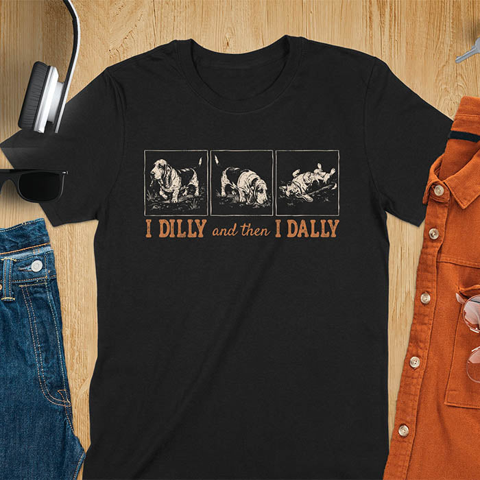Basset hound comic strip tee — three panels: walking, sniffing, flopped over — with text "I DILLY and then I DALLY" in bold retro typography, black