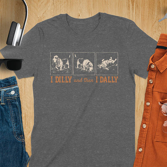 Basset hound comic strip tee — three panels: walking, sniffing, flopped over — with text "I DILLY and then I DALLY" in bold retro typography, dark heather