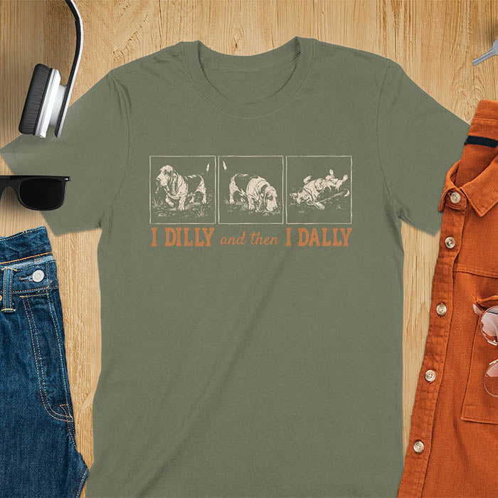 Basset hound comic strip tee — three panels: walking, sniffing, flopped over — with text "I DILLY and then I DALLY" in bold retro typography, military green