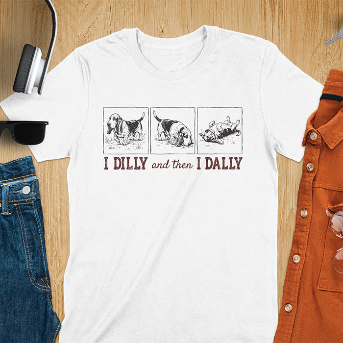 Basset hound comic strip tee — three panels: walking, sniffing, flopped over — with text "I DILLY and then I DALLY" in bold retro typography, white