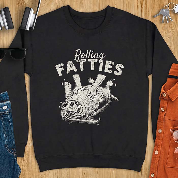 Black sweatshirt with a graphic of a basset hound lying on its back while a pair of hands knead its rolled up folds like dough and the text Rolling Fatties